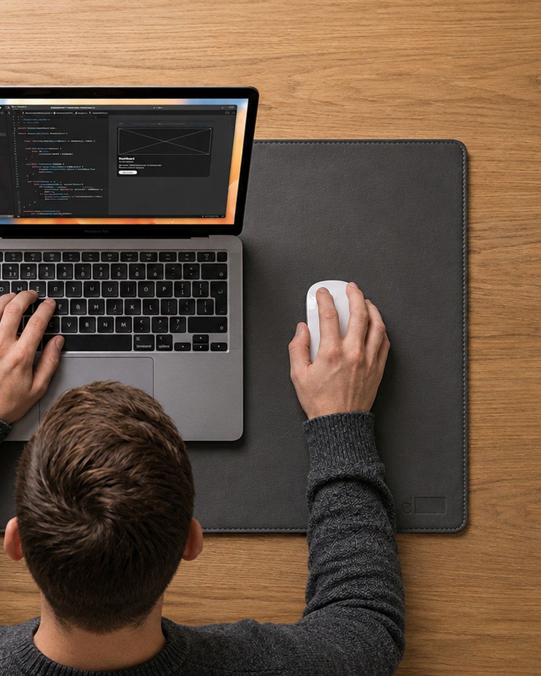 Person using a laptop with a mouse on a wooden desk